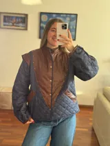 Chaleco acolchado con frente de cuero marrón y espalda de tela azul con diseño de rombos.