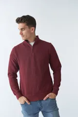 Buzo de algodón color bordó, con cuello alto y medio cierre frontal. Tiene logo bordado y puños en las mangas.