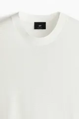 Remera blanca de algodón con tejido de punto calado, cuello redondo y corte estándar.