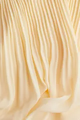 Pollera larga color amarillo pálido, de gasa plisada, con cintura alta con elástico fino y forro interior.