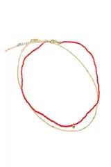 Gargantilla doble con cadena dorada y collar de cuentas rojas.