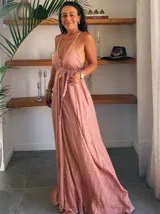 Vestido largo blanco con finas rayas verticales en lurex dorado. Presenta un escote profundo en V con tirantes finos que se anudan en la nuca (estilo halter) y un corte imperio con frunces en la cintura.