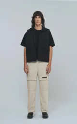 Pantalón cargo beige de corte recto con bolsillos laterales y etiqueta con logo en la pierna.