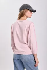 Remera rosa viejo de manga larga con hombros ligeramente abullonados y puños ajustados.