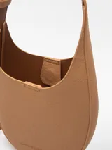 Bandolera pequeña color tostado, con textura granulada, un compartimento y cierre magnético. Tiene asa larga regulable y logo grabado.