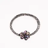 Collar de tres hilos de cuentas negras con dije de flor de cristal tornasol.