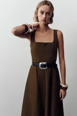Vestido marrón midi de escote cuadrado y tirantes anchos, con cinturón negro y falda evasé. Cierre trasero con cremallera oculta.