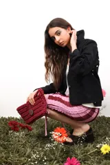 Bolso de mano tejido a crochet en trapillo grueso color borgoña, con asa corta y cierre con botón metálico plateado con logo.