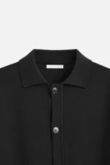 Camisa de punto color negro, corte relaxed fit, con cuello solapa, manga larga y cierre frontal con botones.