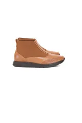 Botín Chelsea color caramelo de cuero vacuno liso con detalle texturizado efecto escama en el talón. Tiene inserciones elásticas laterales, forro 100% de cuero y plantilla de látex.