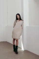 Vestido color beige de punto suave, con escote en V, mangas largas, largo a la rodilla, aberturas laterales y fit holgado.