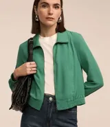 Campera bomber color beige, confeccionada en tejido airflow, con cuello solapa, cierre frontal con cremallera, mangas largas y puños/bajo elásticos.