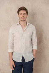 Camisa de manga larga color beige con rayas verticales blancas, confeccionada en lino. Tiene cuello clásico, corte regular y cierre frontal con botones.