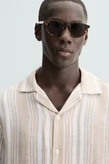 Camisa de hombre a rayas verticales color beige y blanco, de corte relaxed fit, manga corta y cuello bowling.