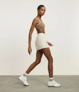 Top deportivo color marrón con breteles anchos y doble tira, copa desmontable, detalles contrastantes en color crema, escote en U delantero y escote en V en la espalda. Confeccionado en microfibra.