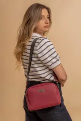 Bandolera pequeña de textura símil cuero color caramelo/marrón, con dos compartimentos principales con cierre. Correa ancha ajustable de tela negra con inscripción en relieve.