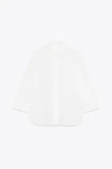 Camisa blanca de cuello solapa y manga larga con puños. Tiene bordados perforados a tono y cierre frontal con botones ocultos.