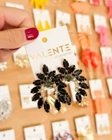 Aretes colgantes de fiesta con base dorada, compuestos por piedras negras facetadas en forma de pétalos y piedras de cristal transparentes y verdes en el centro.