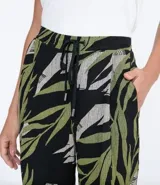 Pantalón pijama fluido de viscosa con estampado de hojas en tonos verde y gris sobre fondo negro. Tiene cintura media con ajuste de cordón con punteras metálicas, bolsillos laterales y pinzas frontales.