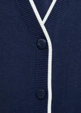 Cárdigan blanco de tejido de punto fino con cuello pico, terminaciones en contraste color rojo, diseño recto, cierre delantero con botones y manga larga.