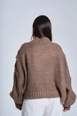 Sweater marrón de punto con cuello alto, diseño de ochos y mangas globo.