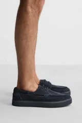 Zapato náutico de cuero color azul marino con cordones finos y suela plana.