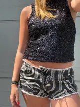 Short de jean con estampado animal print en tonos grises y negros, tiro alto, corte ajustado, con cordones cruzados en la parte delantera y terminación desflecada.