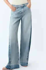 Pantalón de jean de tiro medio con cinco bolsillos, corte wide leg y detalle de tejido con lavado lateral combinado. Cierre frontal con cremallera y botón.