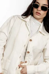 Sobrecamisa de lino y algodón a rayas verticales color crudo, con cuello camisero, cierre frontal con botones y bolsillos de parche en el pecho.