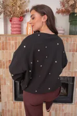 Sweater blanco de algodón con cuello redondo y mangas largas. Decorado con tachas plateadas en el frente y las mangas.