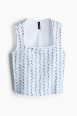 Musculosa blanca con estampado floral celeste, escote cuadrado y ribete de puntilla blanca en cuello y sisas.
