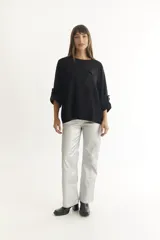 Sweater color beige de tejido de punto suave y liviano, con cuello redondo, manga larga con botón decorativo y bolsillo de parche en el pecho.