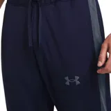 Conjunto deportivo Under Armour de hombre, compuesto por campera con cierre y pantalón largo. Diseño negro con detalles de franjas blancas en mangas y piernas, y logo de la marca en blanco.