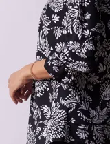 Blusa negra con estampado floral blanco, cuello mao con escote en V y abertura frontal con botones. Manga 3/4 con terminación fruncida.