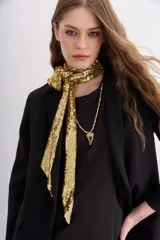 Pashmina delgada de color dorado, recubierta íntegramente por lentejuelas brillantes. Tiene un formato largo y angosto, diseñada para complementar looks de fiesta o eventos nocturnos.