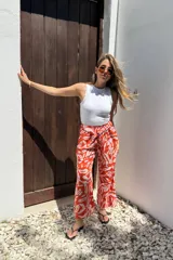 Pantalón de corte amplio, color naranja con estampado abstracto en blanco, cintura elastizada y bolsillos laterales.
