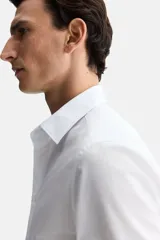 Camisa blanca de corte slim fit, con cuello inglés, tapeta clásica, canesú en la espalda, mangas largas con puños abotonados y bajo levemente redondeado. Confeccionada en tela de fácil planchado.