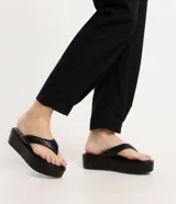 Ojotas negras con plataforma plana, tiras anchas y puntera redonda.