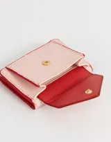 Billetera pequeña de cuerina color rosa claro con solapa en forma de sobre y broche de corazón dorado.