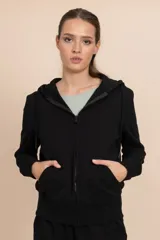 Chaqueta deportiva negra con cierre frontal, capucha con cordones ajustables y bolsillos laterales.