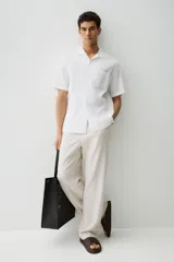 Camisa blanca de manga corta en mezcla de algodón y lino. Modelo con cuello abierto, tapeta lisa y bolsillo superior abierto.
