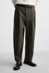 Pantalón verde oliva de corte amplio con pliegues en la parte delantera, bolsillos laterales y traseros de ojal.