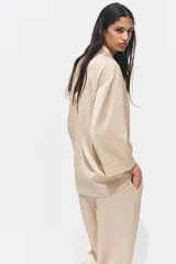 Blazer color beige de cuello solapa y manga tres cuartos. Tejido con efecto arrugado y cierre frontal cruzado con botones negros.