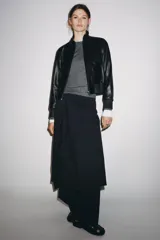 Chaqueta bomber de cuero negra con cuello alto, cierre frontal con cremallera, bolsillos laterales y puños y bajo elásticos.