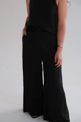 Pantalón negro de lino, de corte palazzo, con cintura alta y cierre con botón.