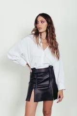 Minifalda negra de cuero ovino con tajo lateral y lazos ajustables en la cintura.