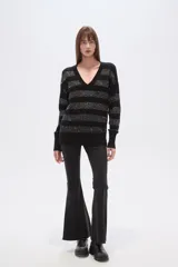 Sweater negro con cuello en V, diseño holgado y mangas largas. Presenta rayas horizontales de lentejuelas plateadas.