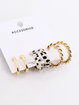 Set de tres pares de aros de metal: un par de aros tipo argolla dorados, un par de aros tipo argolla con estampado animal print blanco y negro, y un par de aros tipo argolla dorados con diseño trenzado.
