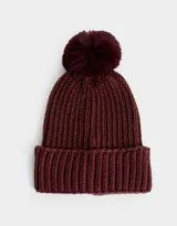 Gorro de lana tejido color borgoña con pompón de piel sintética en la parte superior.
