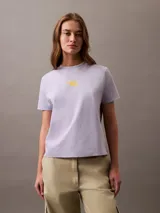 Remera de manga corta color lila de algodón con cuello redondo y logo Calvin Klein aterciopelado en color amarillo en el pecho.